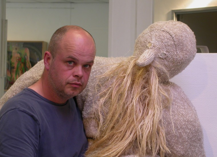 Gijs Assmann poseert met een van zijn beelden/poppen